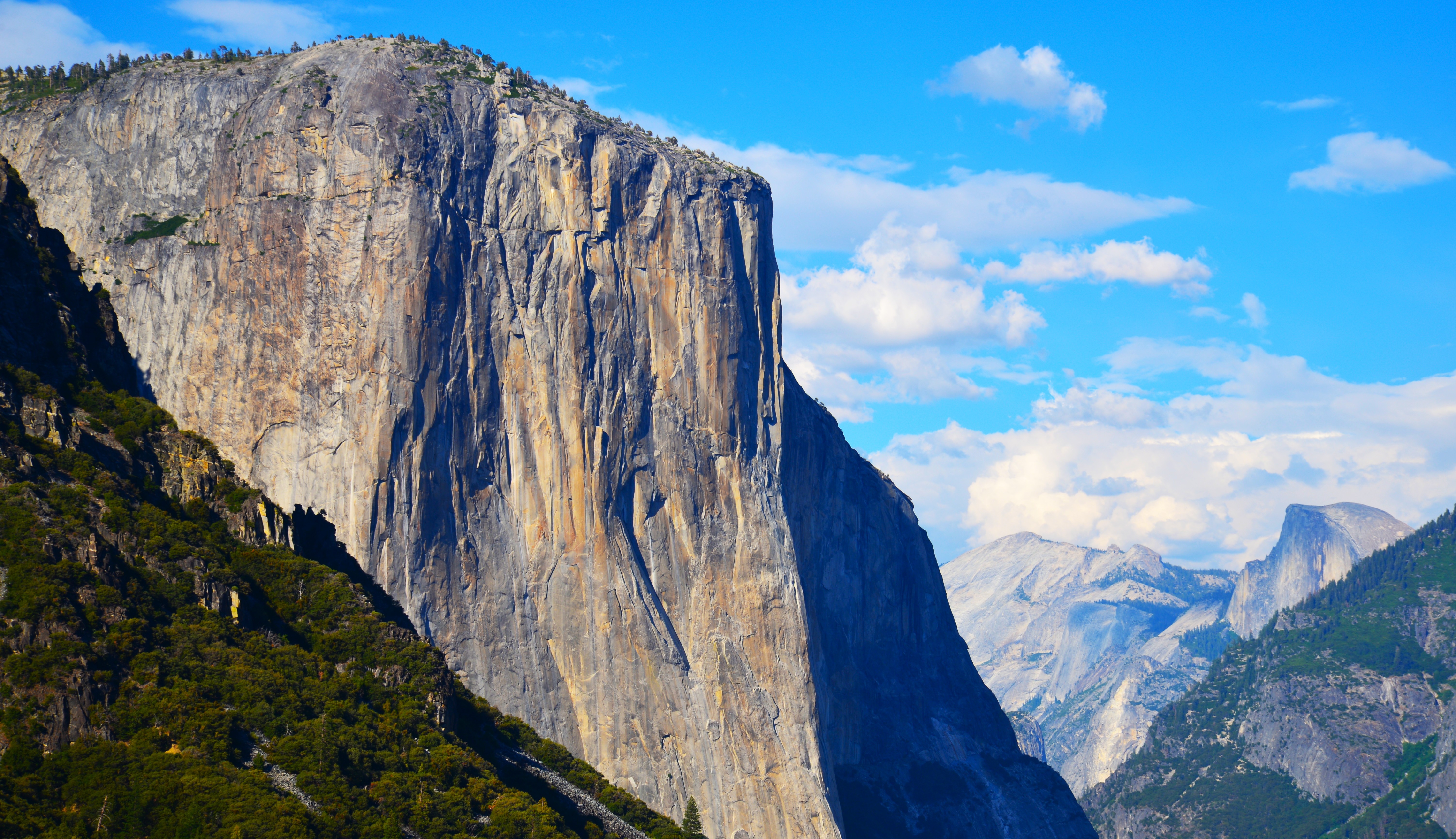 Towering granite cliffs above a forested valley beneath a blue sky